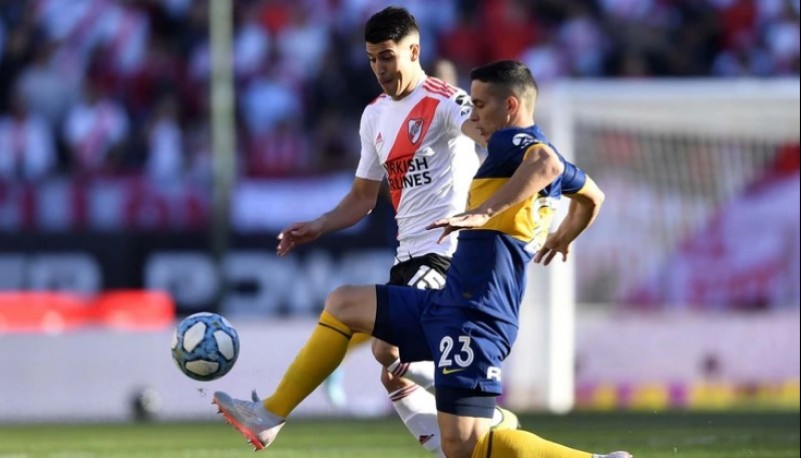 Palacios disputa el balón con Marcone durante el Superclásico disputado este domingo (Foto: Télam)