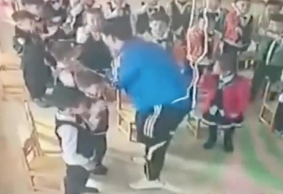 Captura de video del momento en el cual el maestro les dice a los nenes que deben golpearse en la cara. 